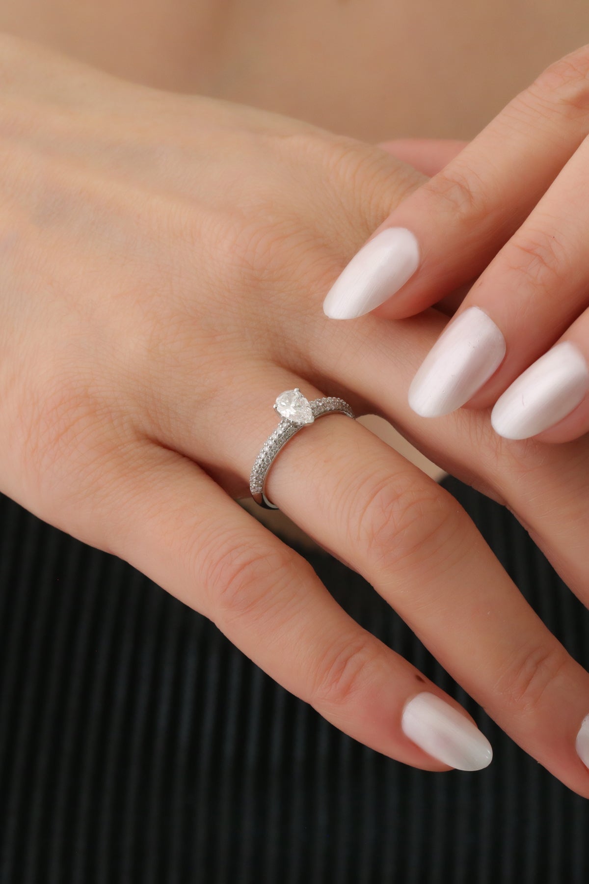 Inel de logodnă din aur alb 18K cu diamant pară și pavé de diamante, prezentat într-un cadru lifestyle